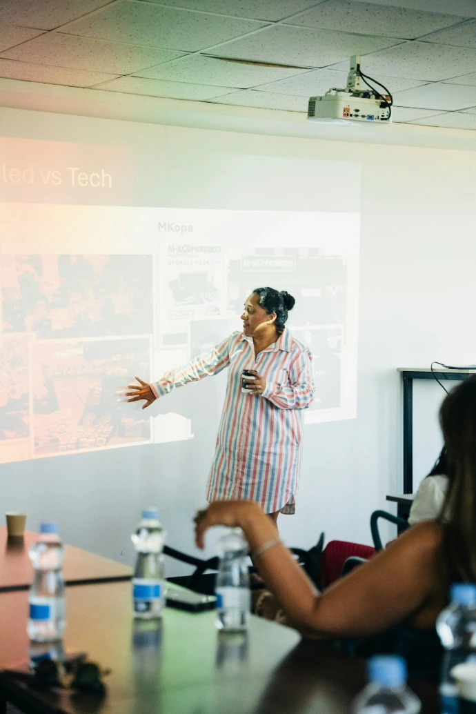 Woman presenting to audience near projector screen